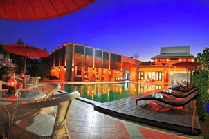 Un hotel moderno con piscina, zona de estar al aire libre y fachada bien iluminada.