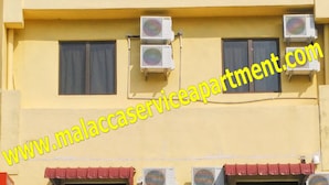 Un edificio con varias unidades de aire acondicionado, un letrero que dice 'DobiDobi' en la fachada y un automóvil estacionado adelante.