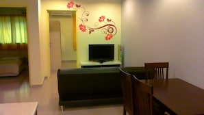 Una sala de estar con televisor, sofá y mesa de comedor.