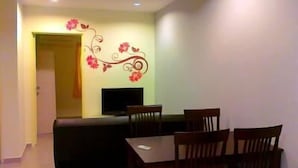 Un comedor con televisor, sillas de madera y un sofá.