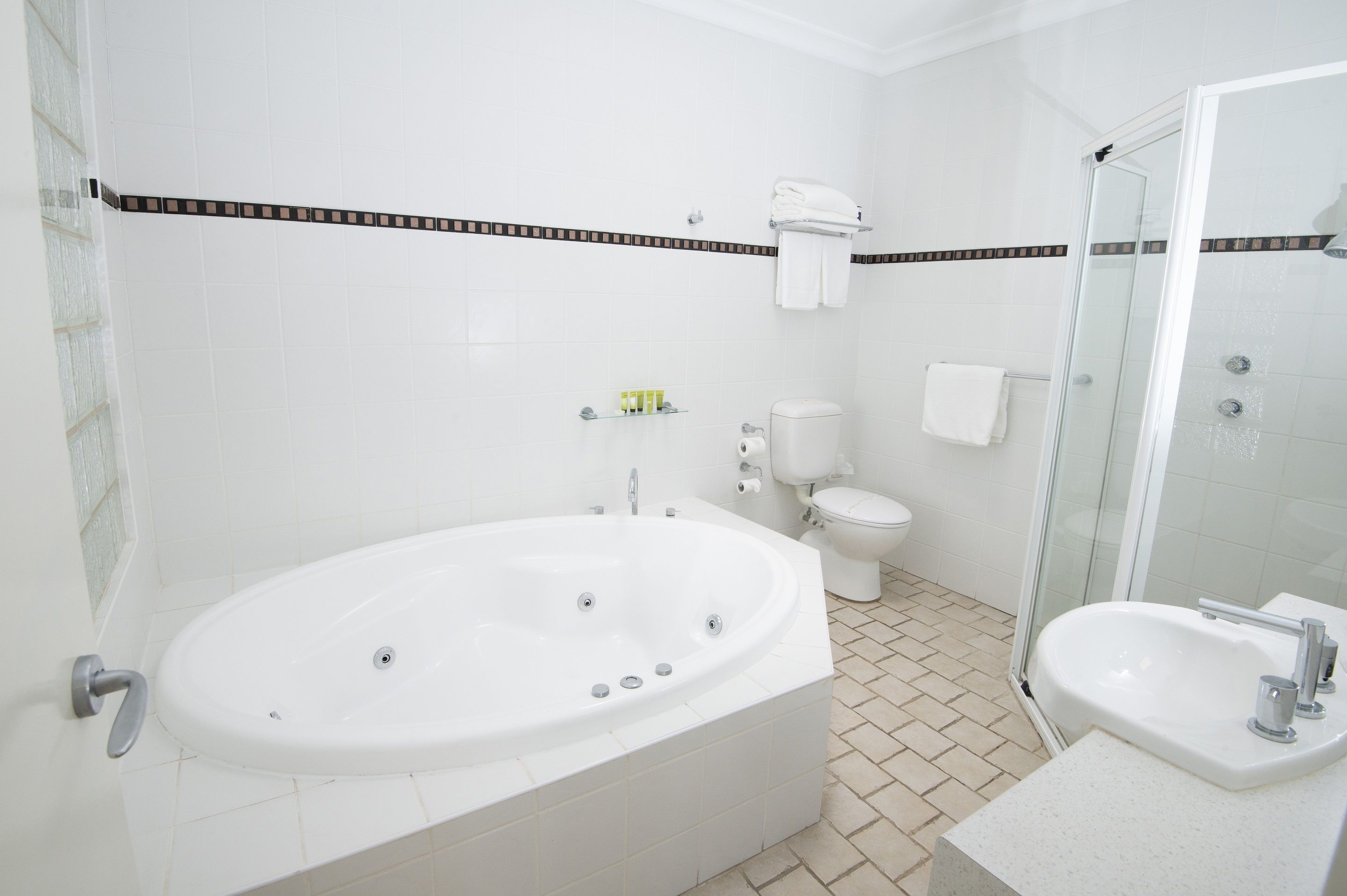 A modern bathroom with a freestanding bathtub, a separate sink, a toilet, and a glass-enclosed shower area.