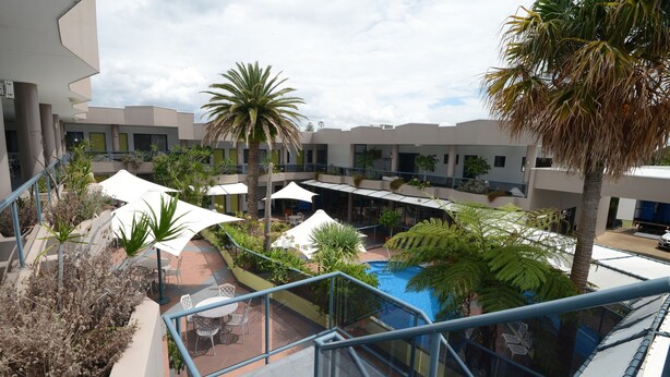 Une cour avec des espaces de détente en plein air, des palmiers et une piscine.