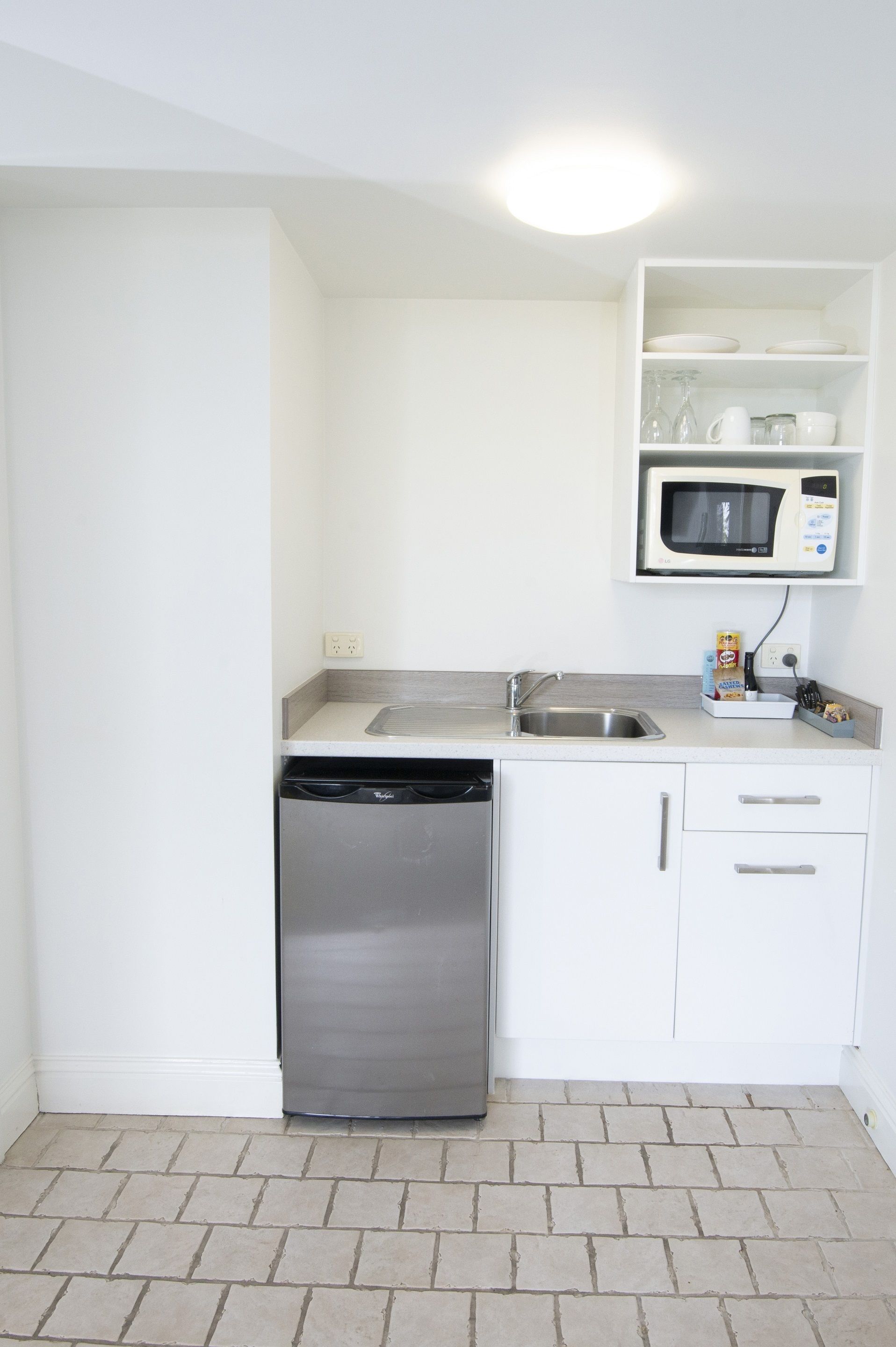 A compact kitchen with a dishwasher, a microwave, and a sink.