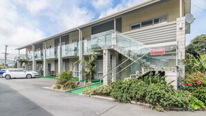 A multi-story motel with a balcony on the second floor, a satellite dish, and a sign indicating a Sky Decoder room. - Avana Suites (Lower Hutt)