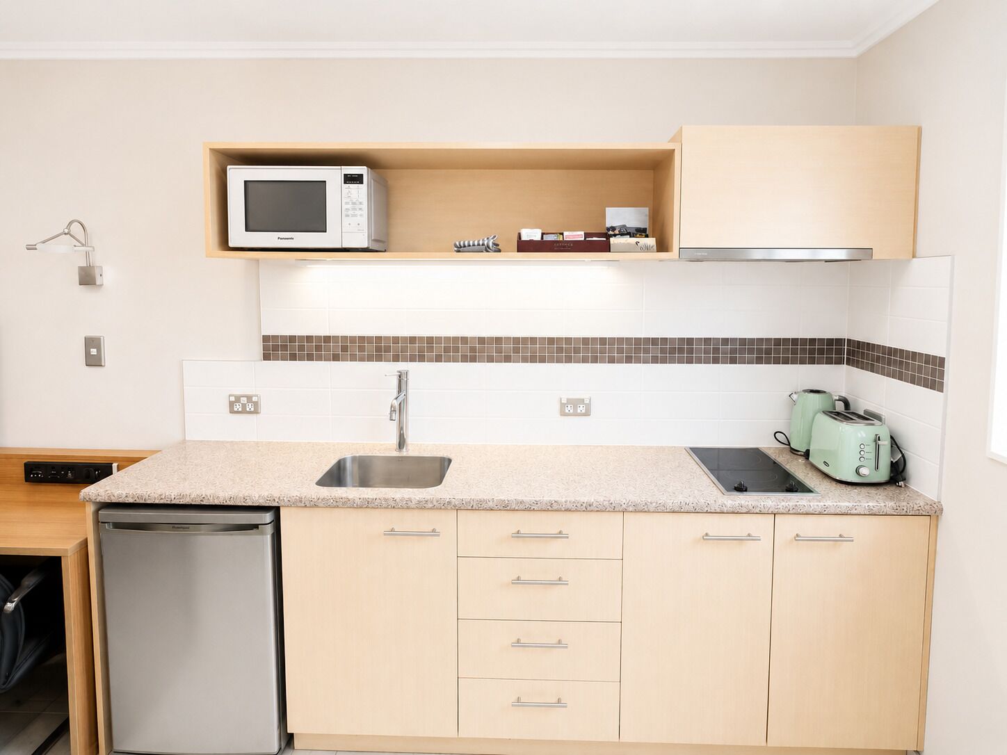 A compact kitchen with a microwave, toaster, and a dishwasher.