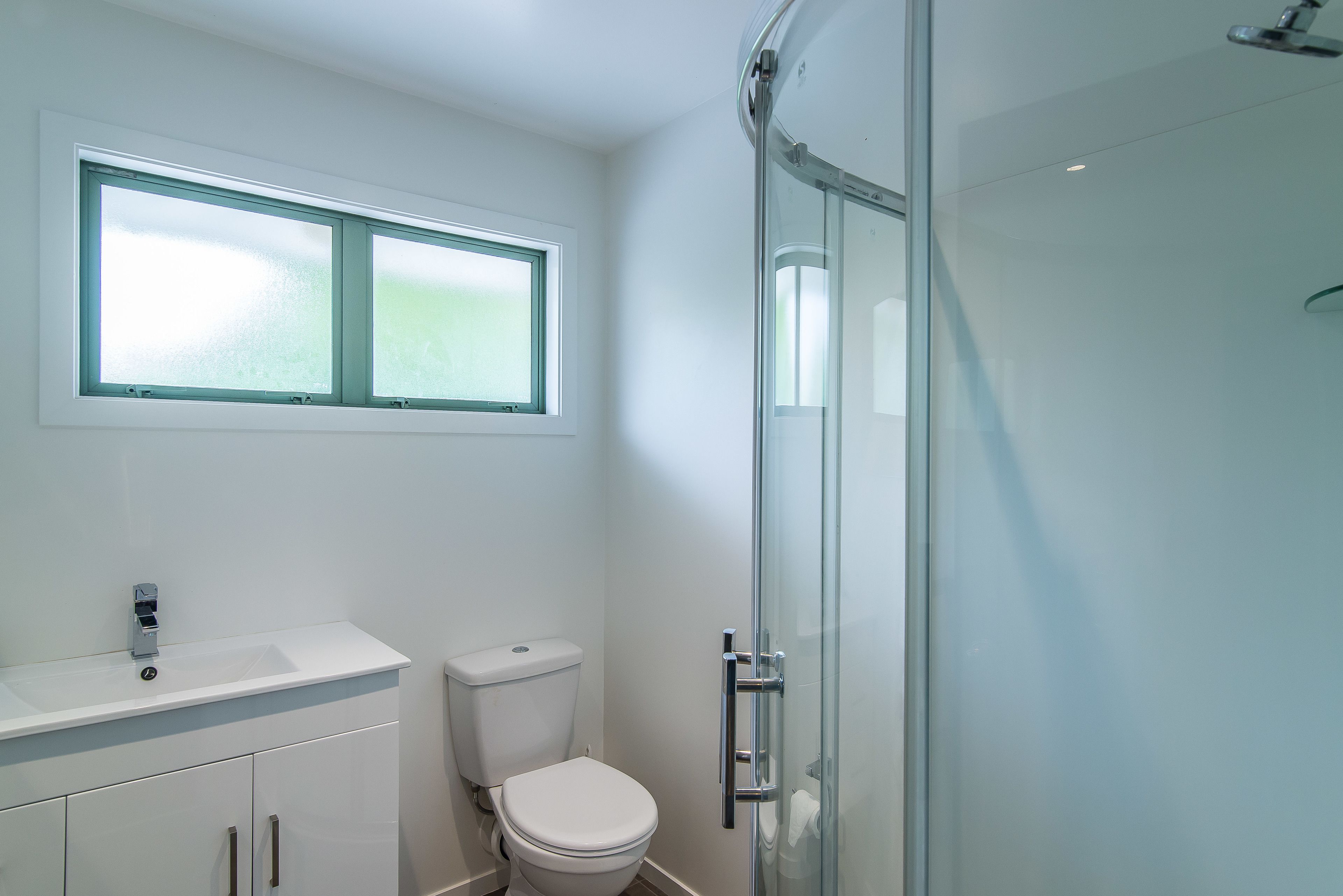 Un baño con lavamanos blanco, inodoro y cabina de ducha de vidrio.