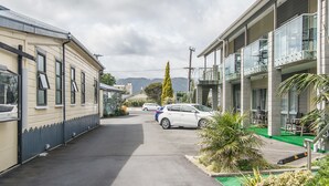 A street view with a row of buildings, a parked car, and a clear sky. - Avana Suites (Lower Hutt)