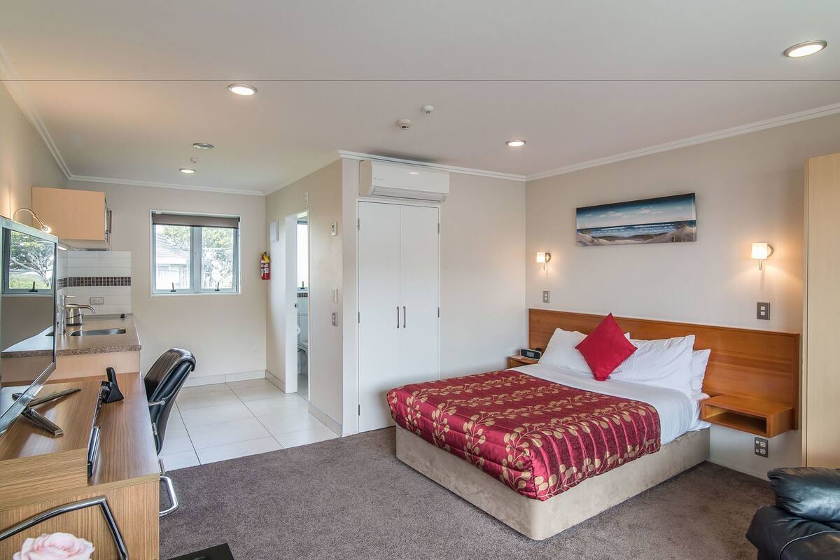 A bedroom with a bed, bedside table, and a painting on the wall.