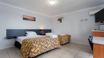 A hotel room with two beds, a desk, a TV, and a painting on the wall.