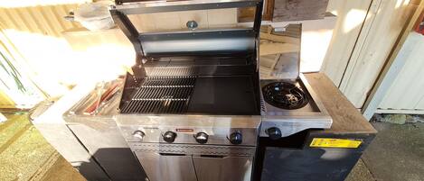 A commercial kitchen with a stainless steel grill, a built-in stove, and a gas burner.