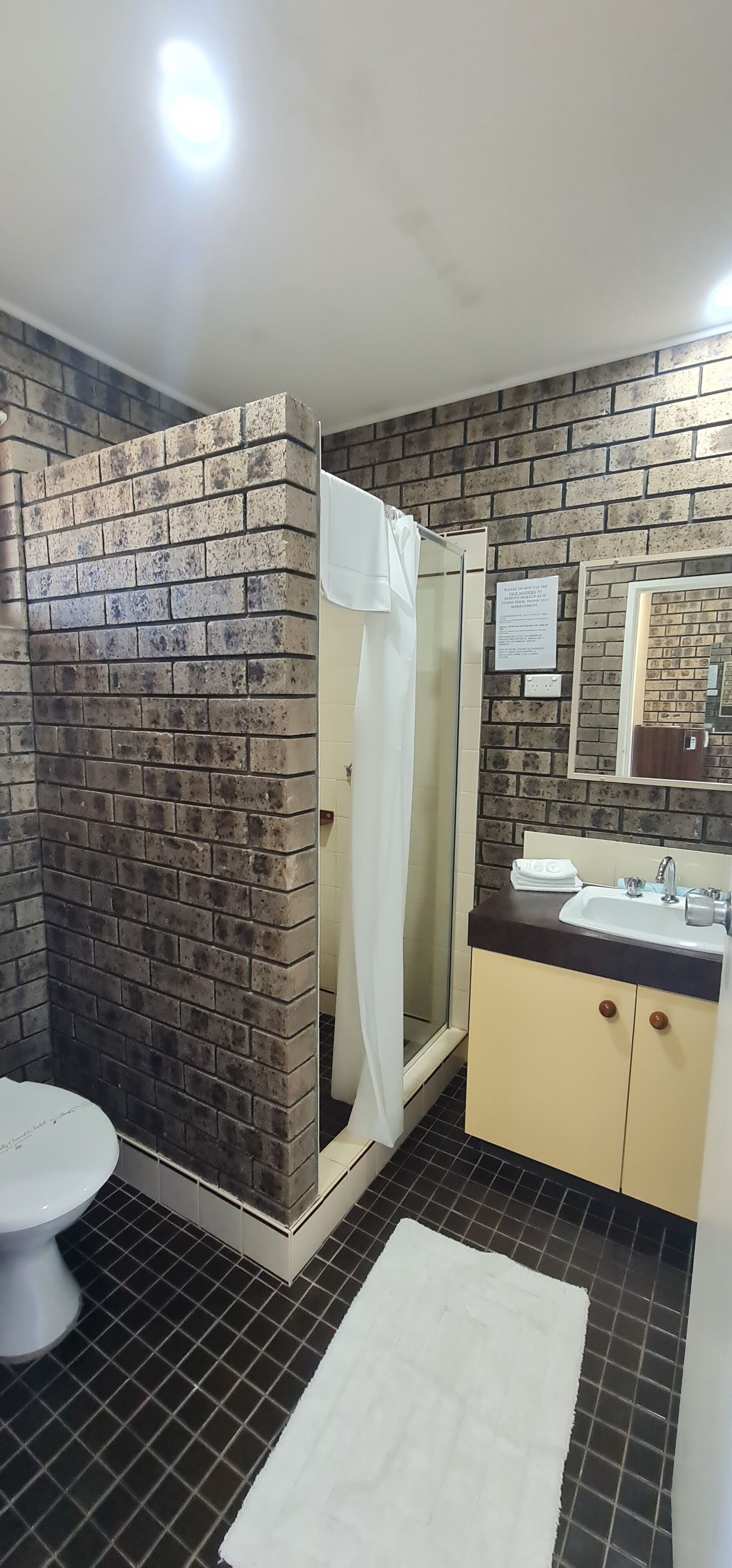 Un baño con ducha, inodoro, lavabo y espejo.