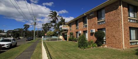 Un motel con recepción, un edificio de ladrillo y un césped bien cuidado.