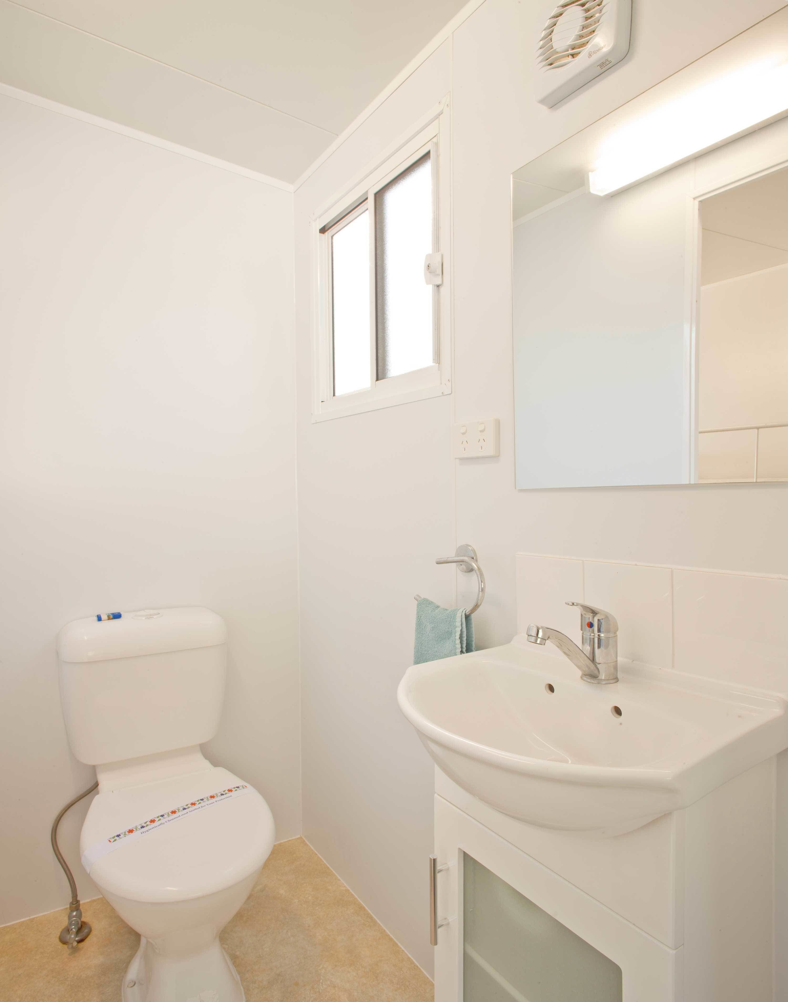 Un baño con inodoro, lavamanos y espejo.