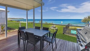 A covered patio with a table and chairs, a grill, and a view of the ocean. - Blue Lagoon Beach Resort (Bateau Bay)