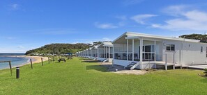 Fileira de casas móveis brancas, com gramado e vista para a praia.
