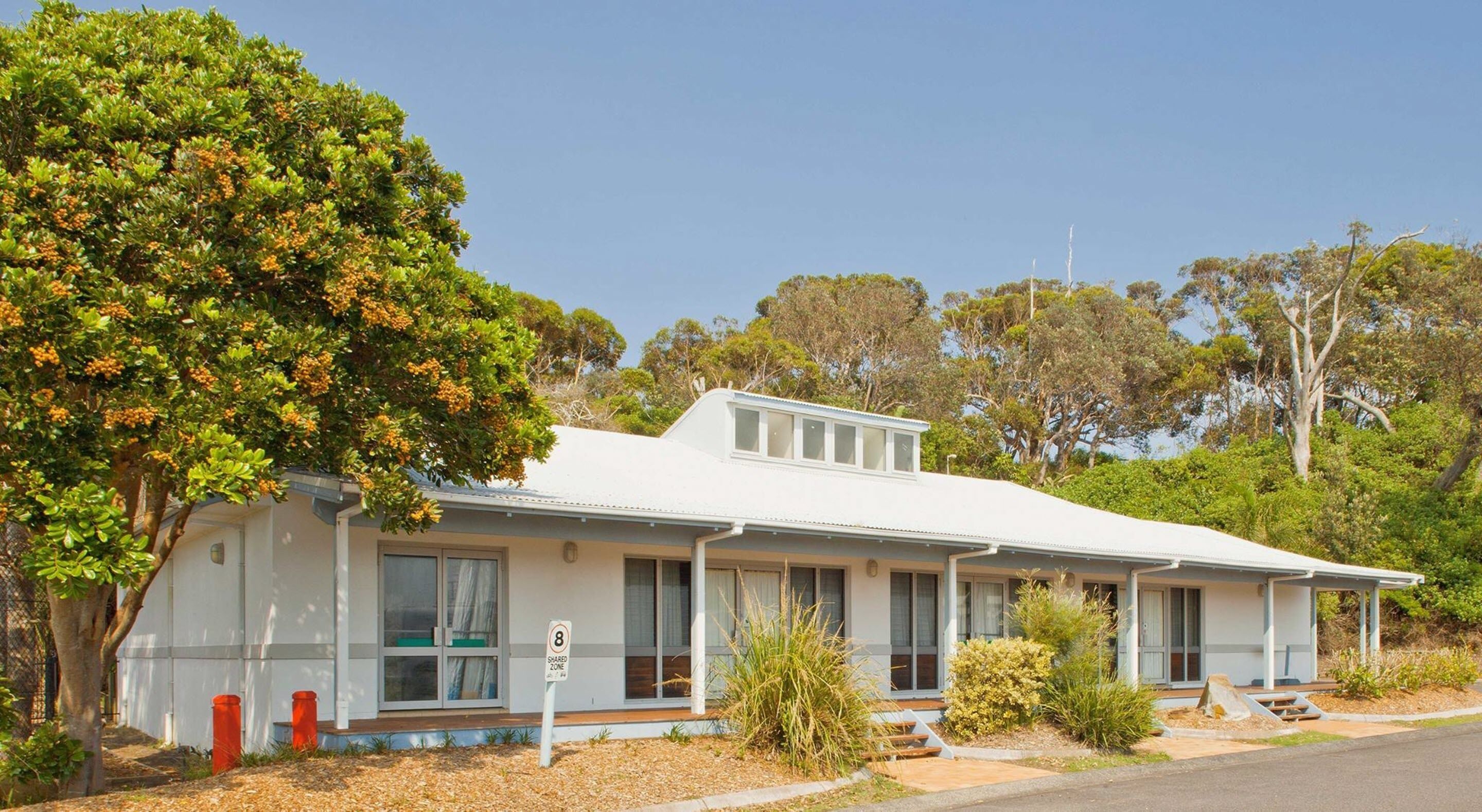 Un motel d’un seul étage, doté d’un toit plat, de grandes fenêtres et d’un petit espace porche.