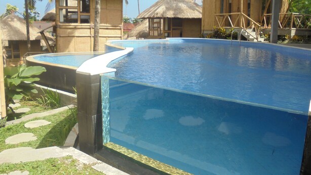 Una piscina con una estructura de techo de paja cerca.