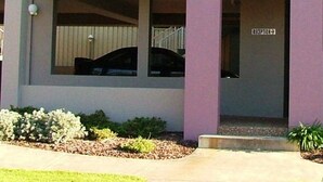 Un edificio de dos pisos con fachada azul y morada, un balcón con barandilla y un letrero en la entrada que dice "AQUARIUS".