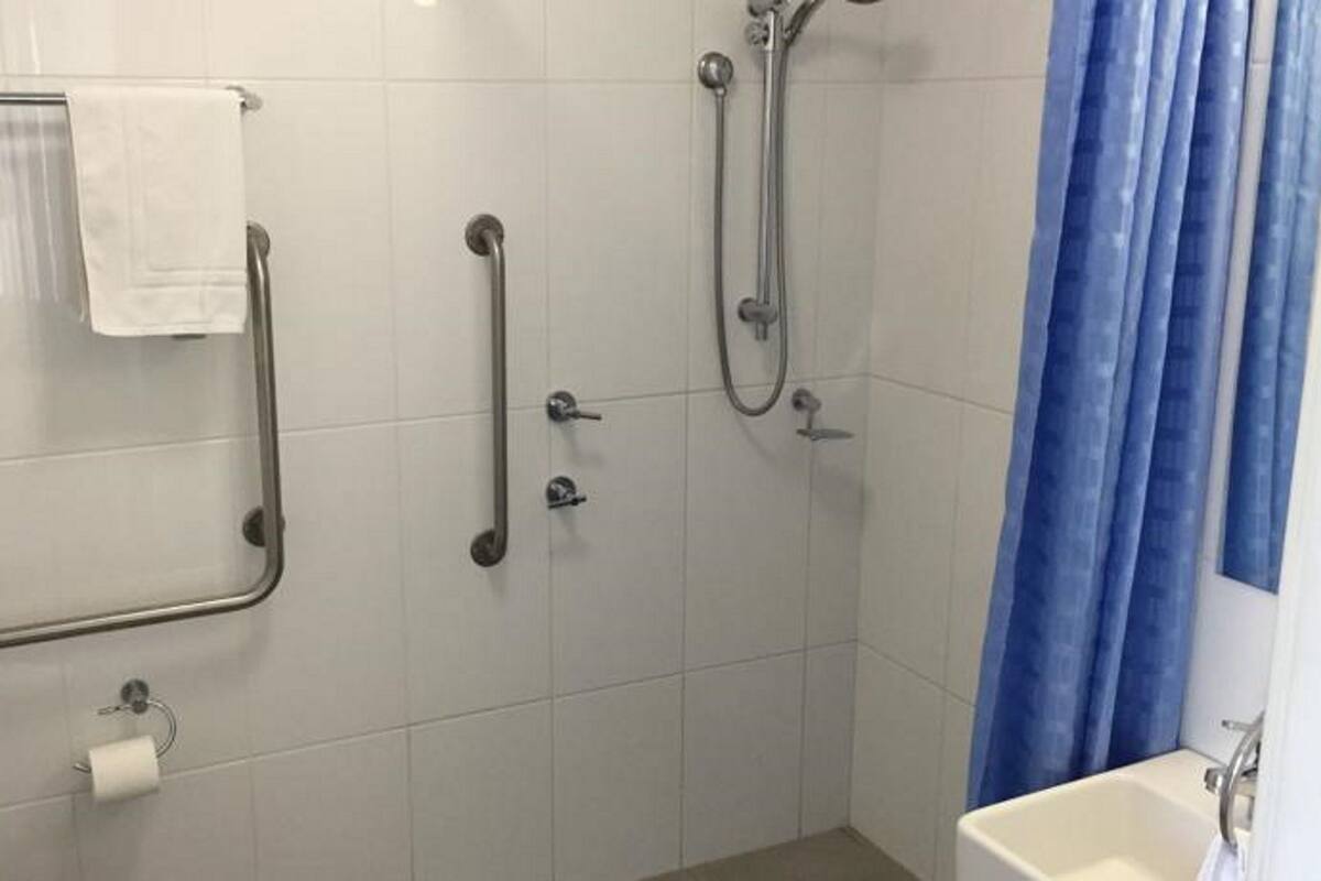 A bathroom with a shower, grab bars, a toilet, and a bathtub.
