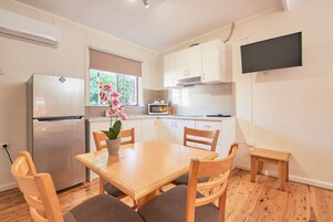 Cocina compacta con refrigerador, microondas y mesa de madera con sillas.