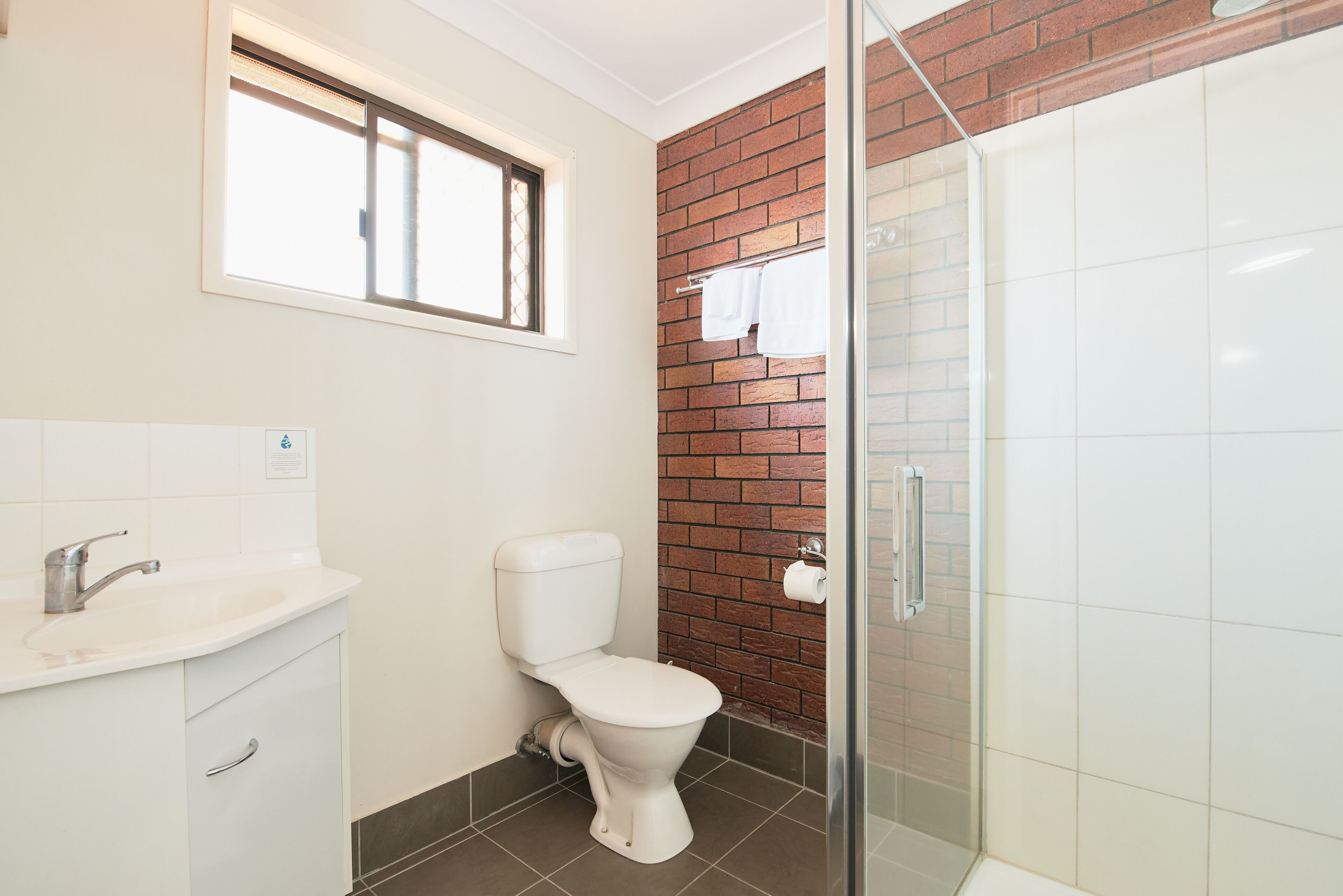 A bathroom with a white toilet, a sink, and a glass shower enclosure.