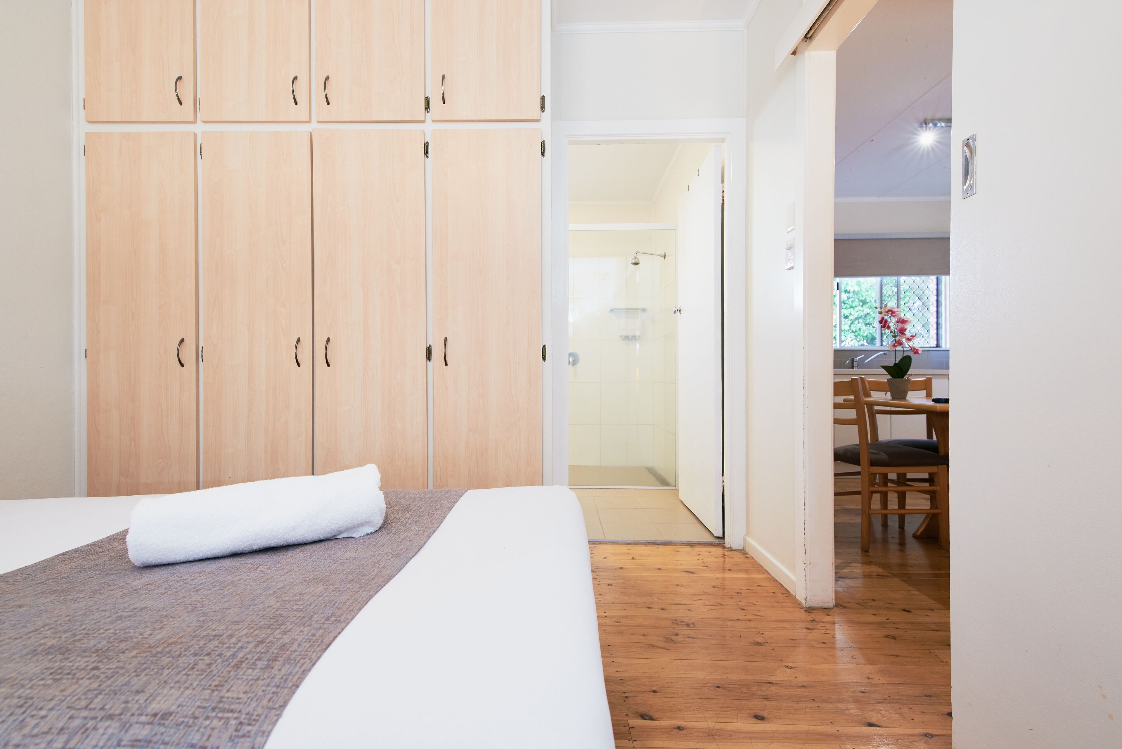 Une chambre d’hôtel avec un lit, une armoire en bois et une salle de bain visible à travers une porte ouverte.