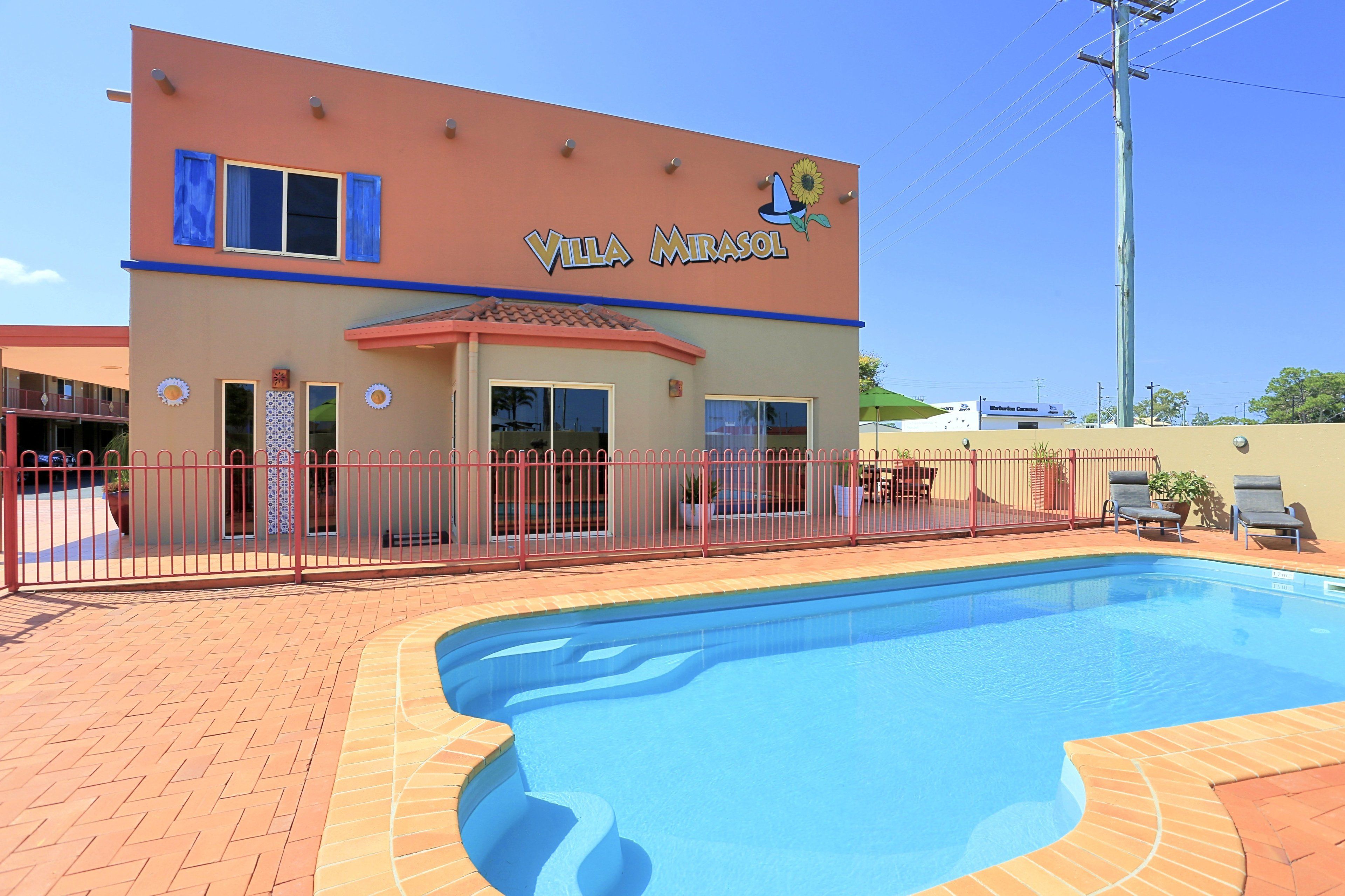 Um edifício chamado Villa Mirasol com piscina e um pátio cercado.
