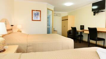 A hotel room with two beds, a desk with a chair, a television, and a framed picture on the wall.