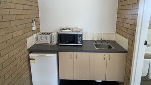 Eine kompakte Küche mit Mikrowelle, Toaster und kleinem Kühlschrank.