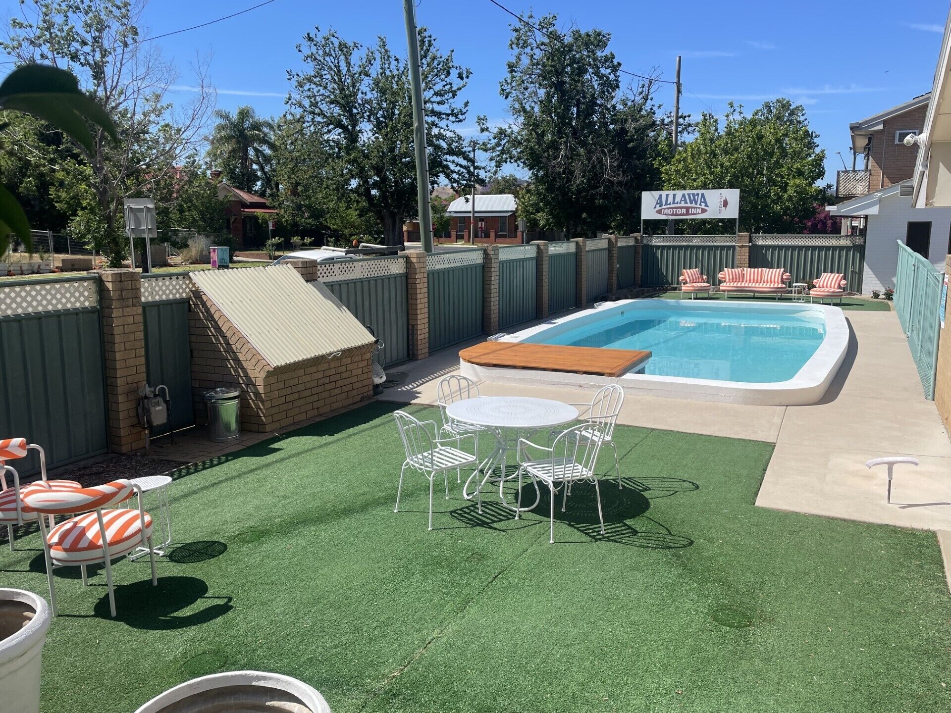 A backyard with a swimming pool, a covered patio area, and outdoor seating.