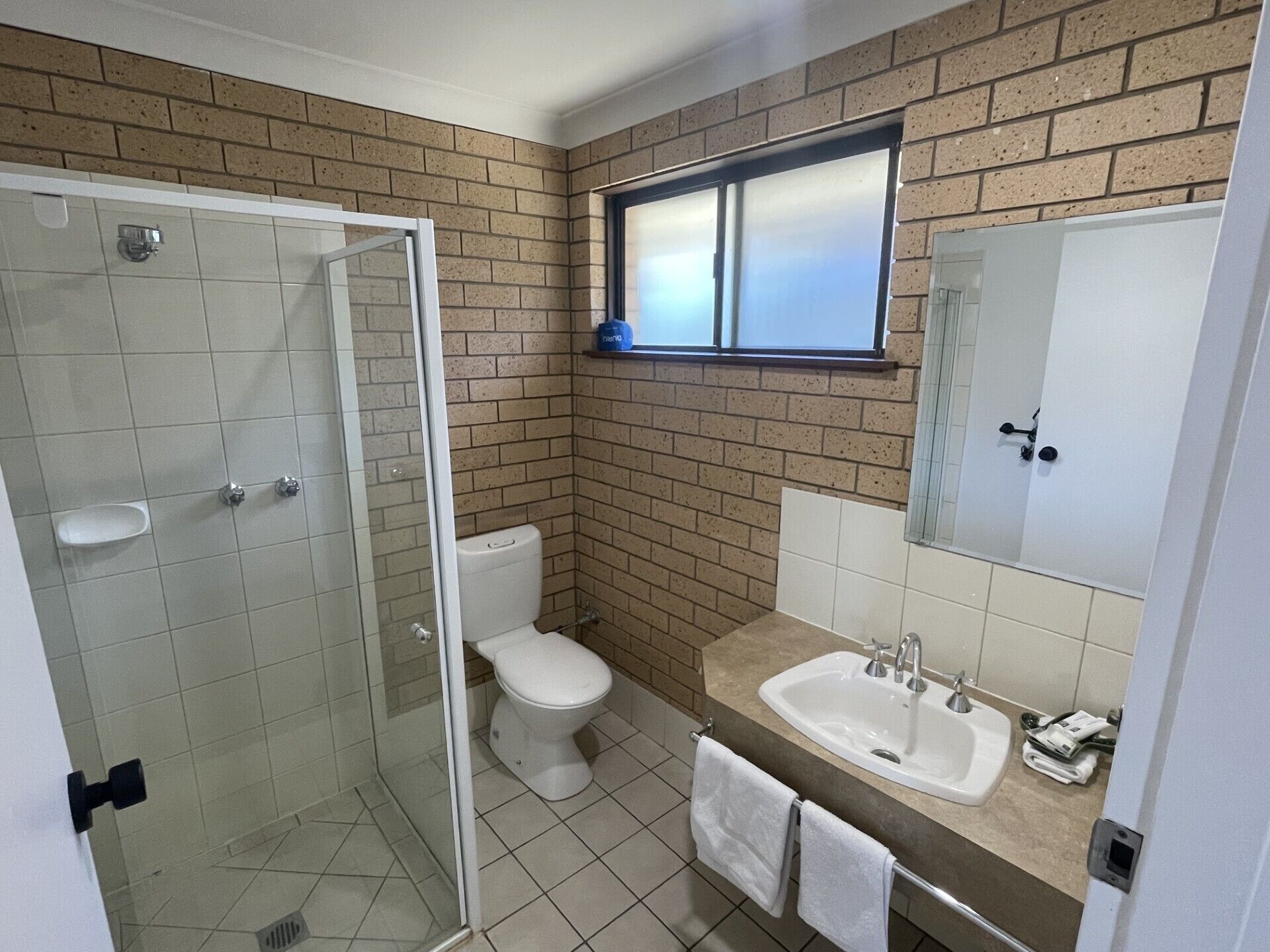 Ein Badezimmer mit Duschkabine aus Glas, Toilette, Waschbecken und Spiegel.