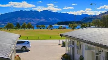 A hotel with a view of mountains and a lake. There is a car parked in front.
