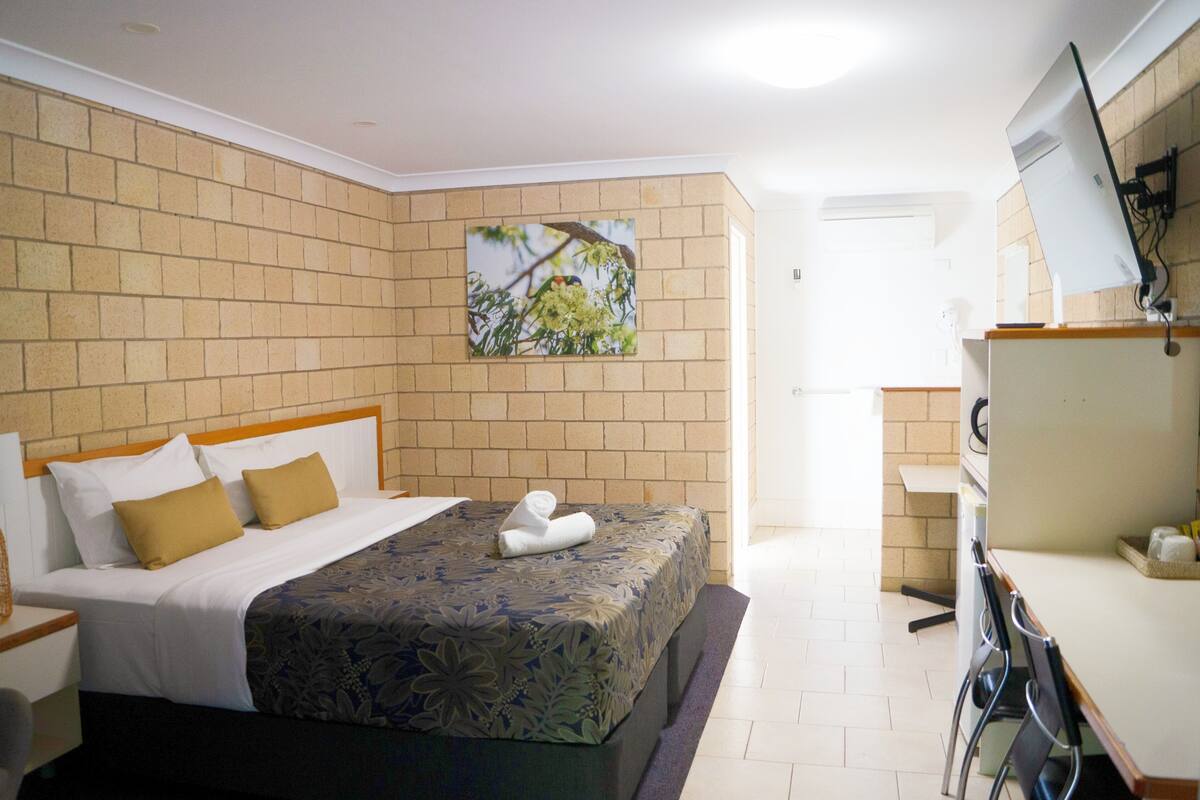 A hotel room with a bed, a desk, and a chair.