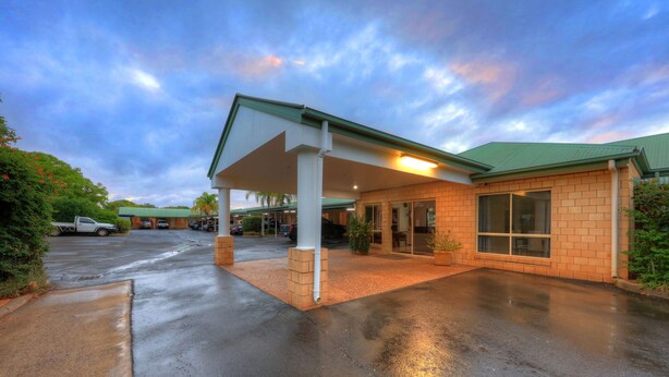 A hotel with a covered parking area, a brick building, and a green roof. - Jacaranda Country Motel (St. George)