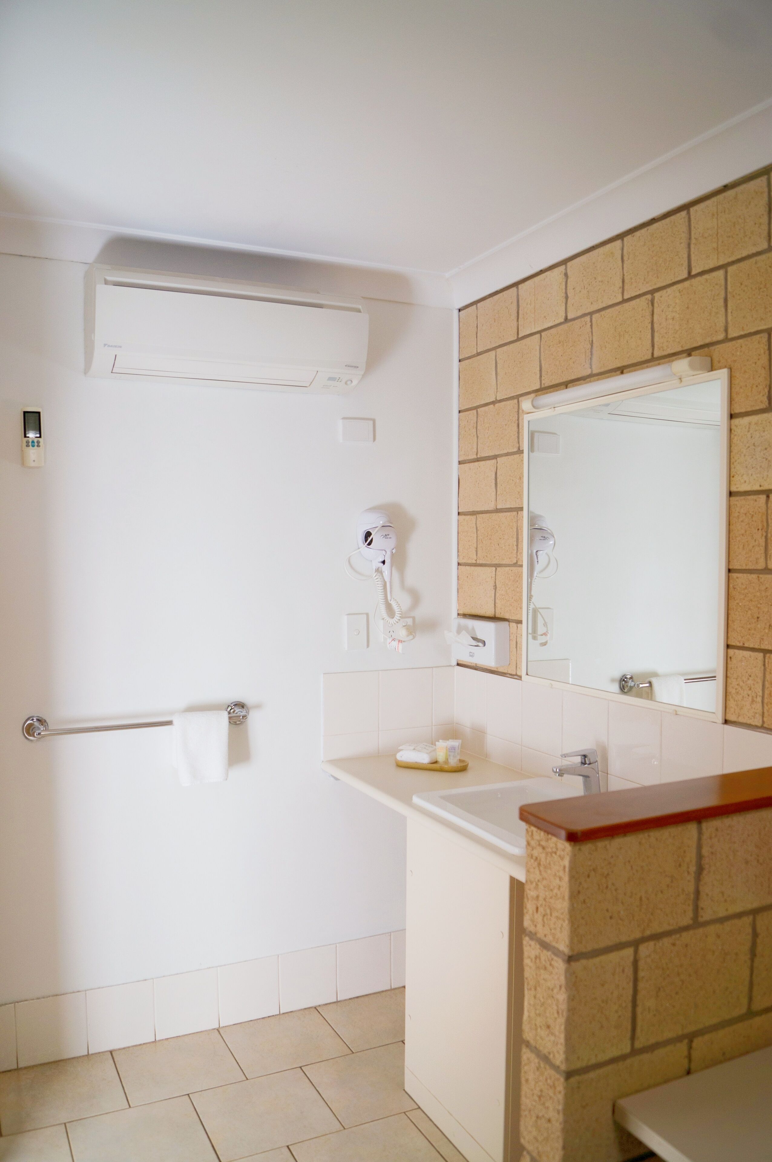 A bathroom with a white sink, a mirror, a towel rack, and a hairdryer.