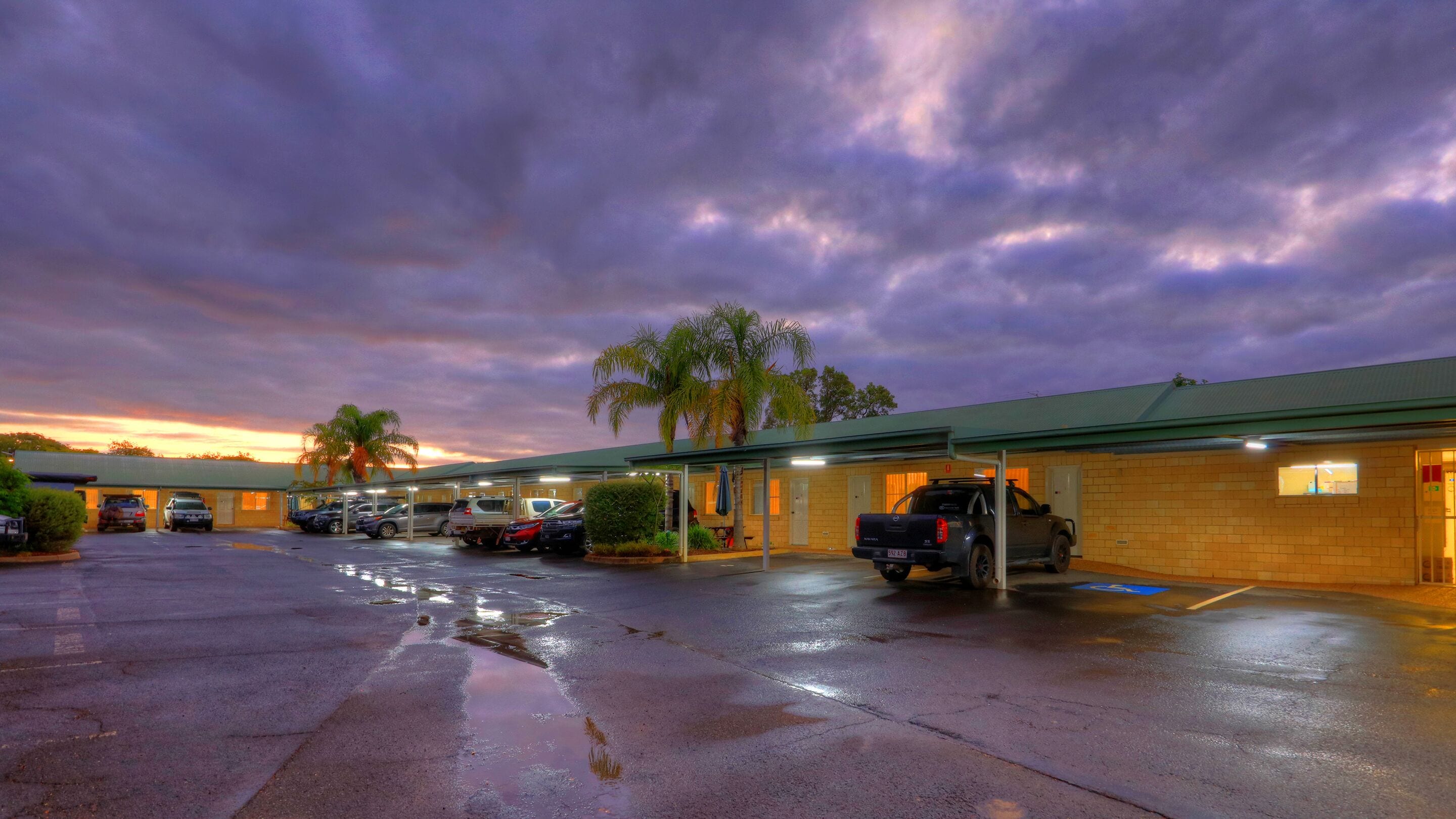 A motel with a covered parking area and a row of rooms.