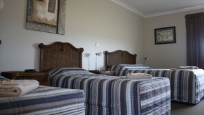 Une chambre d’hôtel avec deux lits, chacun doté de draps à rayures, d’une tête de lit en bois, d’une table de chevet avec une lampe et d’un tableau encadré au mur.