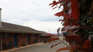 Un motel avec une allée en gravier, un bâtiment en briques et une porte bleue.