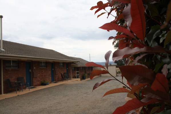A motel with a gravel driveway, a brick building, and a blue door.