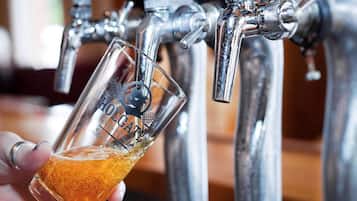 A hand holding a glass of beer at a tap.