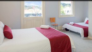 Een hotelkamer met twee bedden, een stoel en uitzicht op buiten.