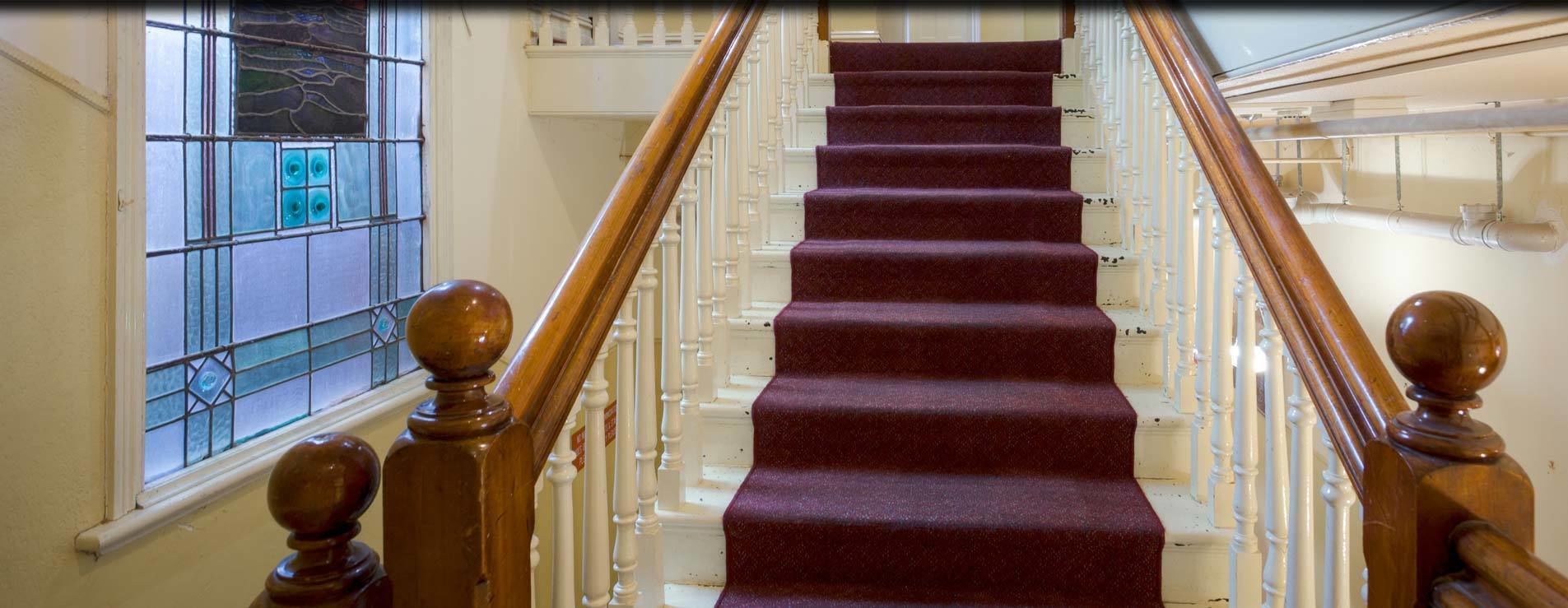 A staircase with wooden balusters and a red carpeted landing.