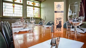Een eettafel gedekt met wijnglazen, bestek en een menukaart houder.
