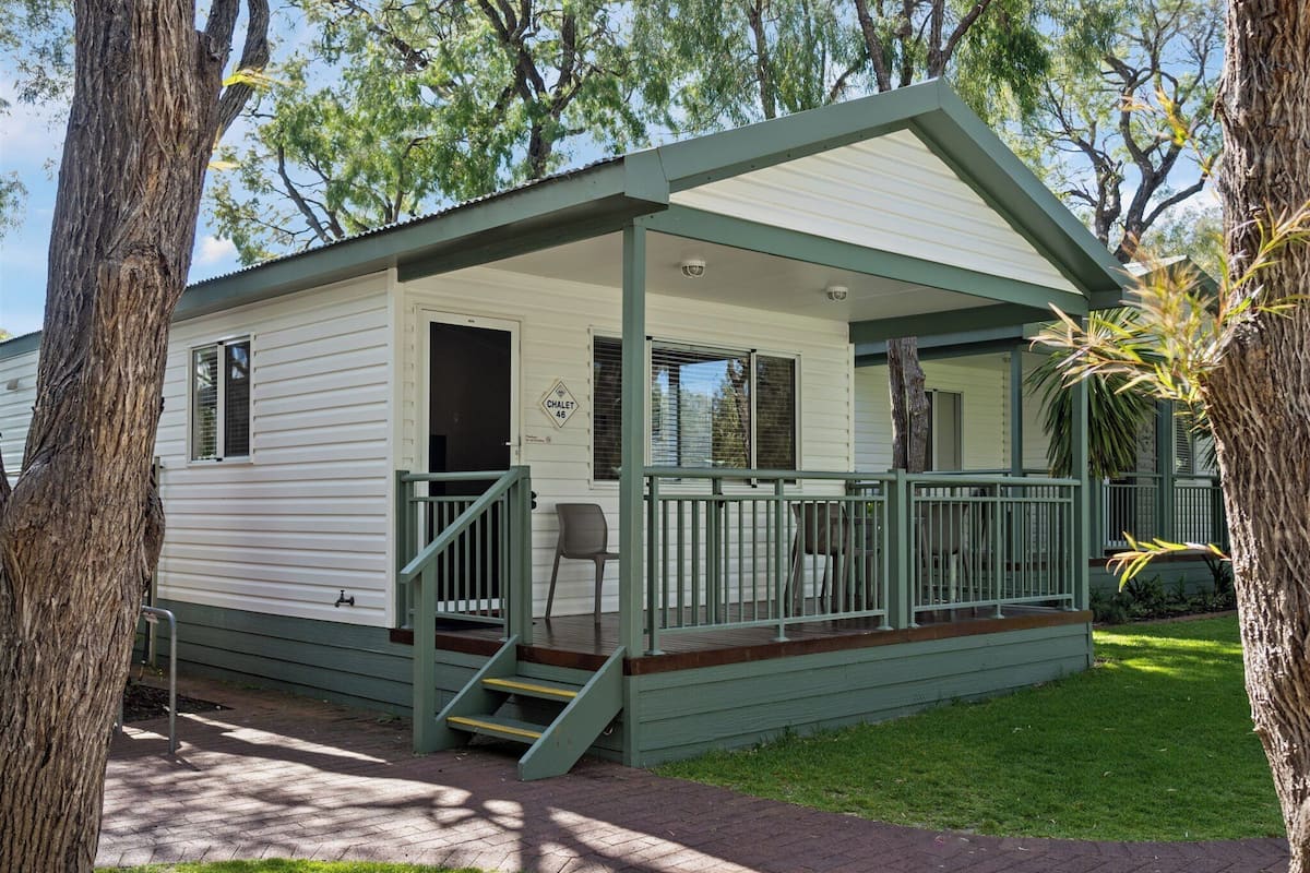 A small, single-story mobile home with a covered porch and a small set of stairs leading to the entrance.