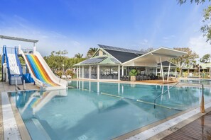 A swimming pool with a rainbow slide, a covered seating area, and solar panels. - Mandalay Holiday Resort and Tourist Park (Broadwater)