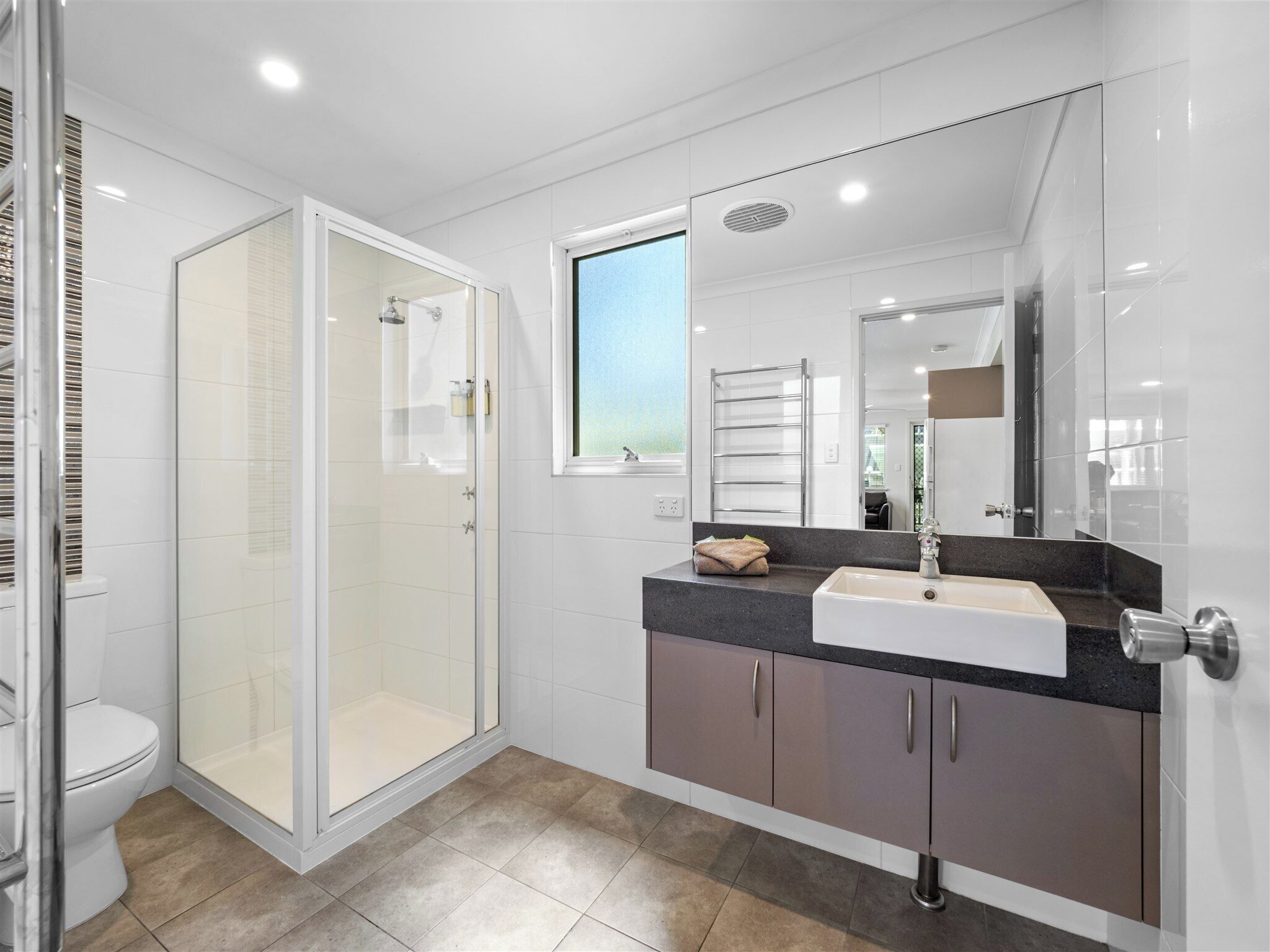 A modern bathroom with a glass shower enclosure, a sink with a vanity, and a large mirror.