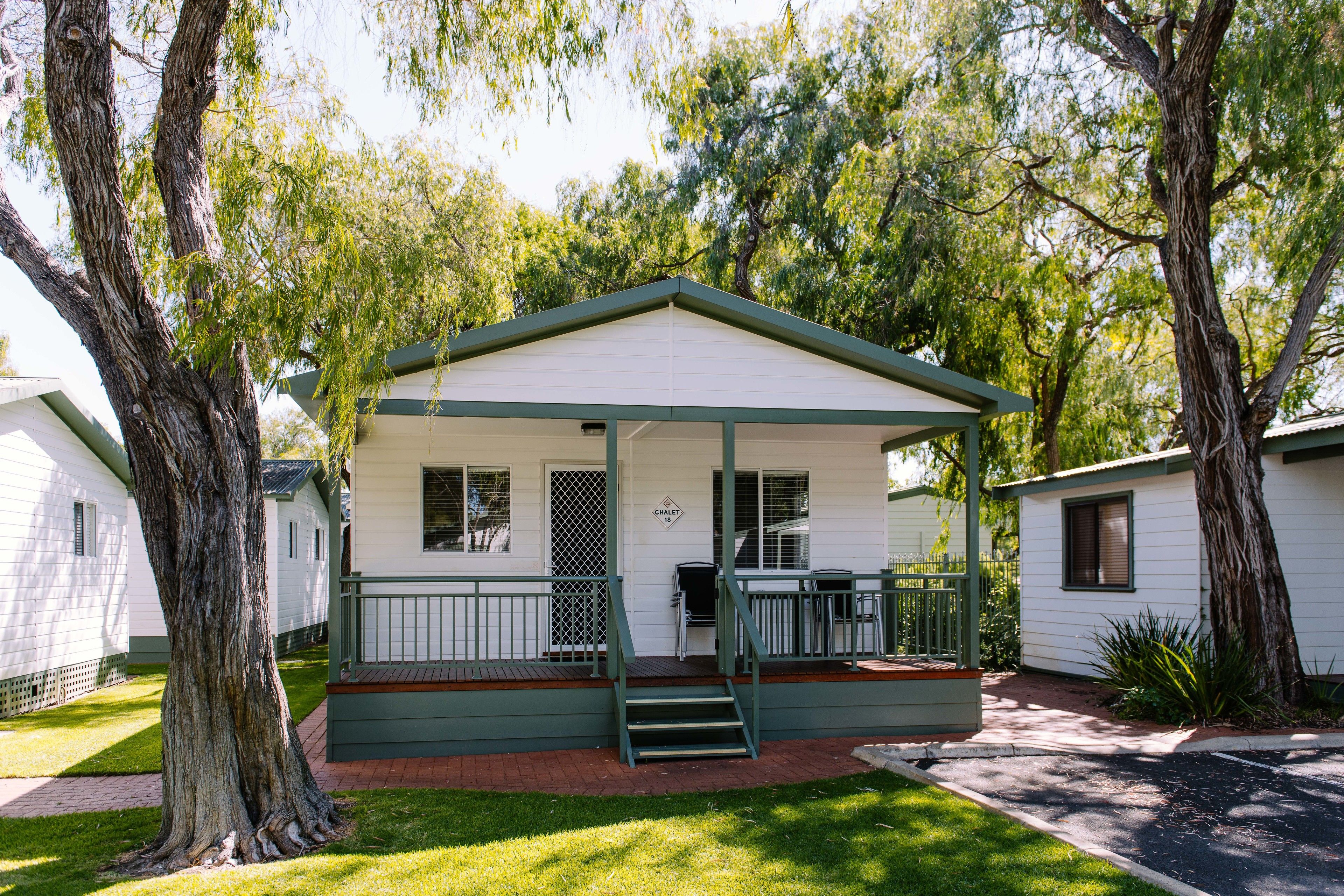 A small, single-story mobile home with a porch, a small deck, and a staircase leading to the entrance.