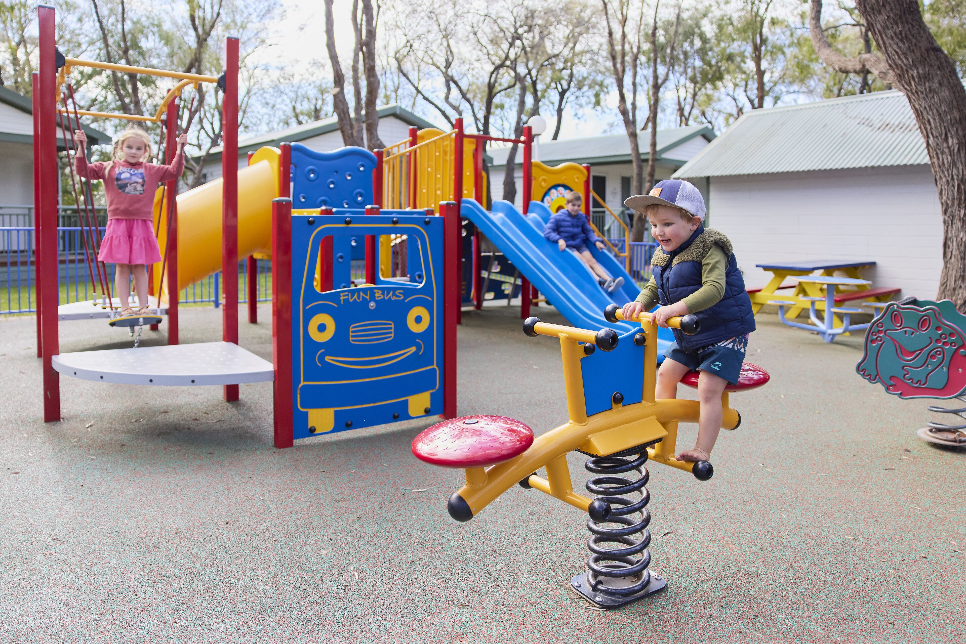 A playground with a slide, climbing structures, and a seesaw.