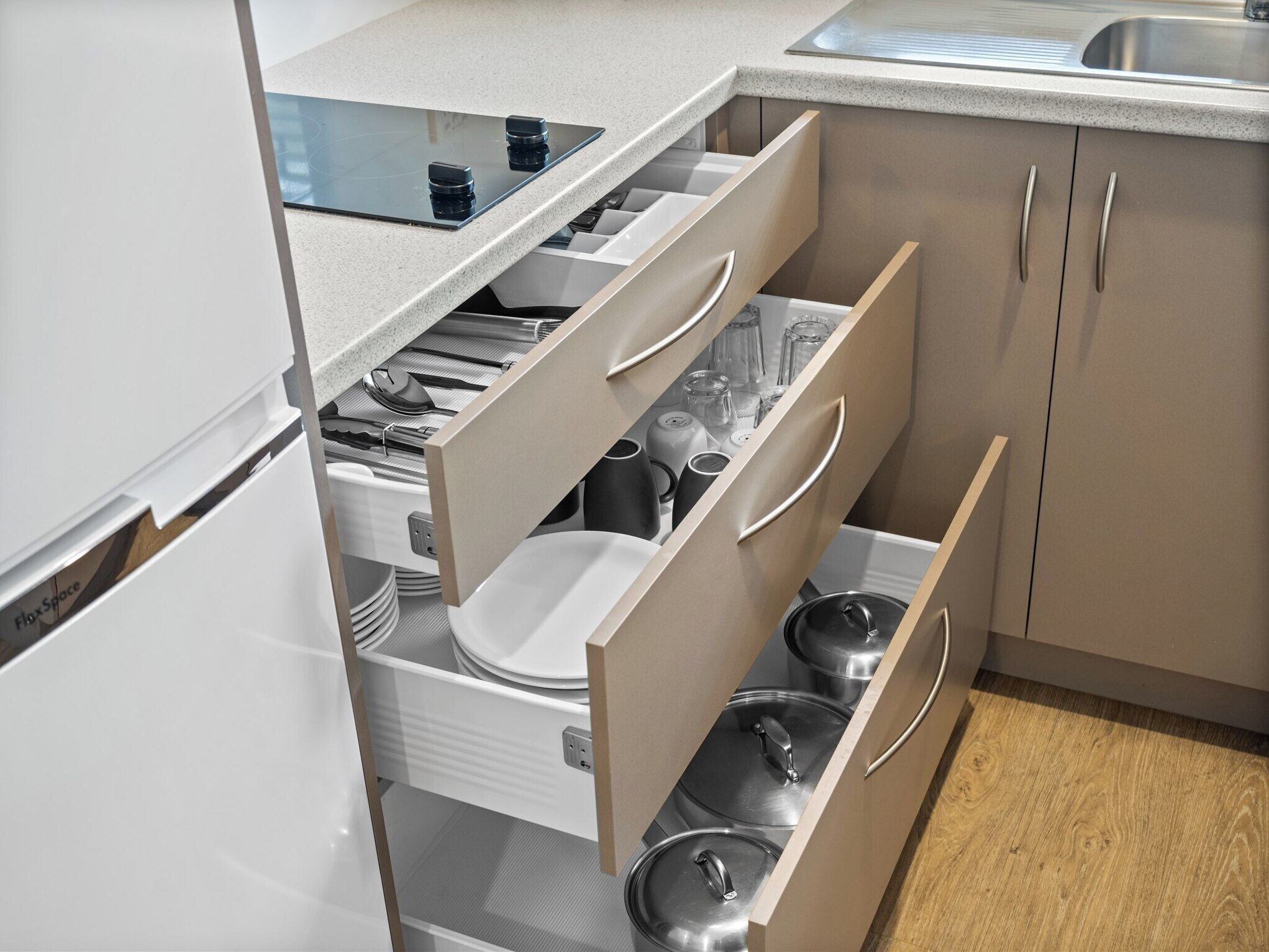 Une cuisine équipée d’une cuisinière intégrée, de meubles blancs et d’un évier.
