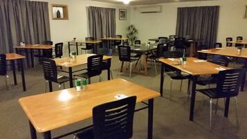 A conference room with multiple tables and chairs, arranged in a U-shape.